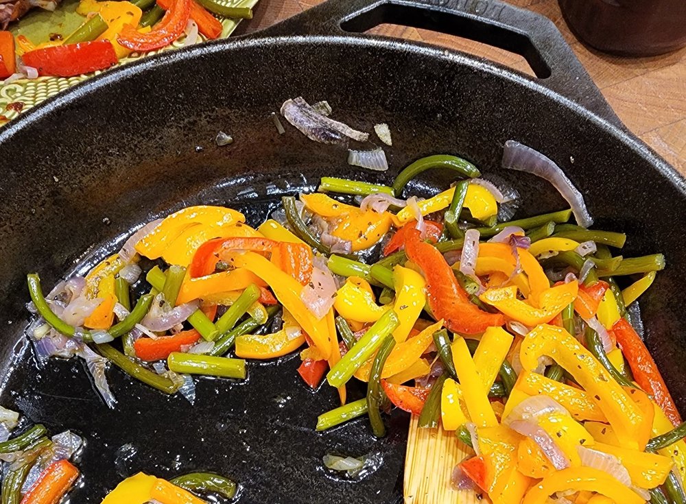 Sautéed colorful bell peppers, green beans, and onions in a cast iron skillet, showcasing vibrant vegetables for a healthy recipe.