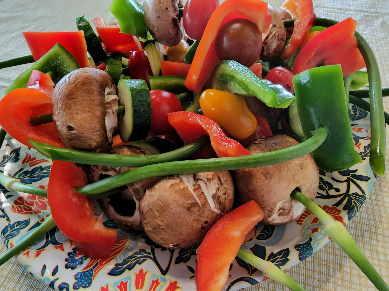 Colorful assortment of fresh vegetables including mushrooms, bell peppers, cherry tomatoes, and zucchini arranged on a decorative plate, ideal for a healthy recipe post.